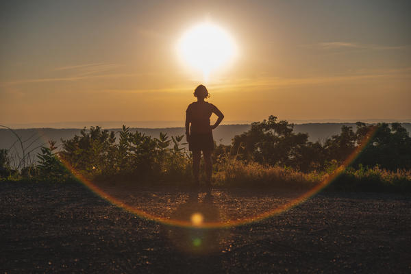 A woman's silhouette against a setting sun overlook.
