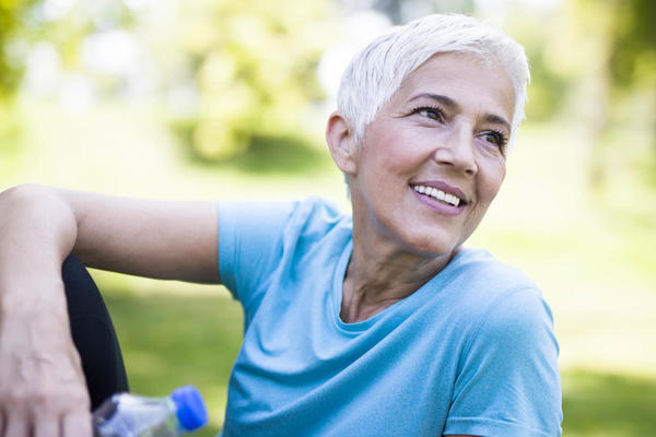 A white woman with white hair sitting on a green lawn