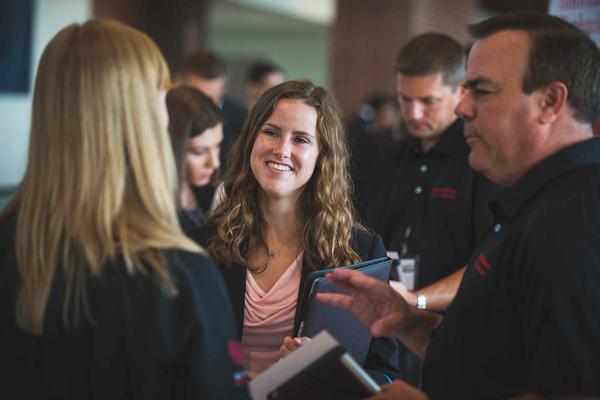 A female student speaking with two potential employers.