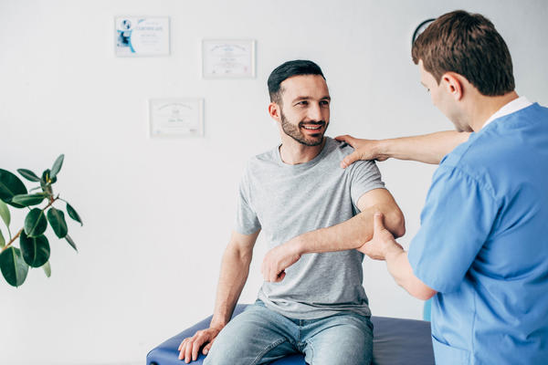A man receiving physical therapy from a male medical staff person.