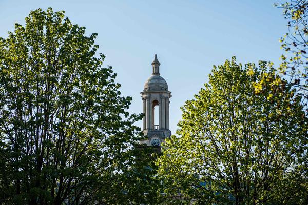 Old Main bell tower framed by treetops in Spring